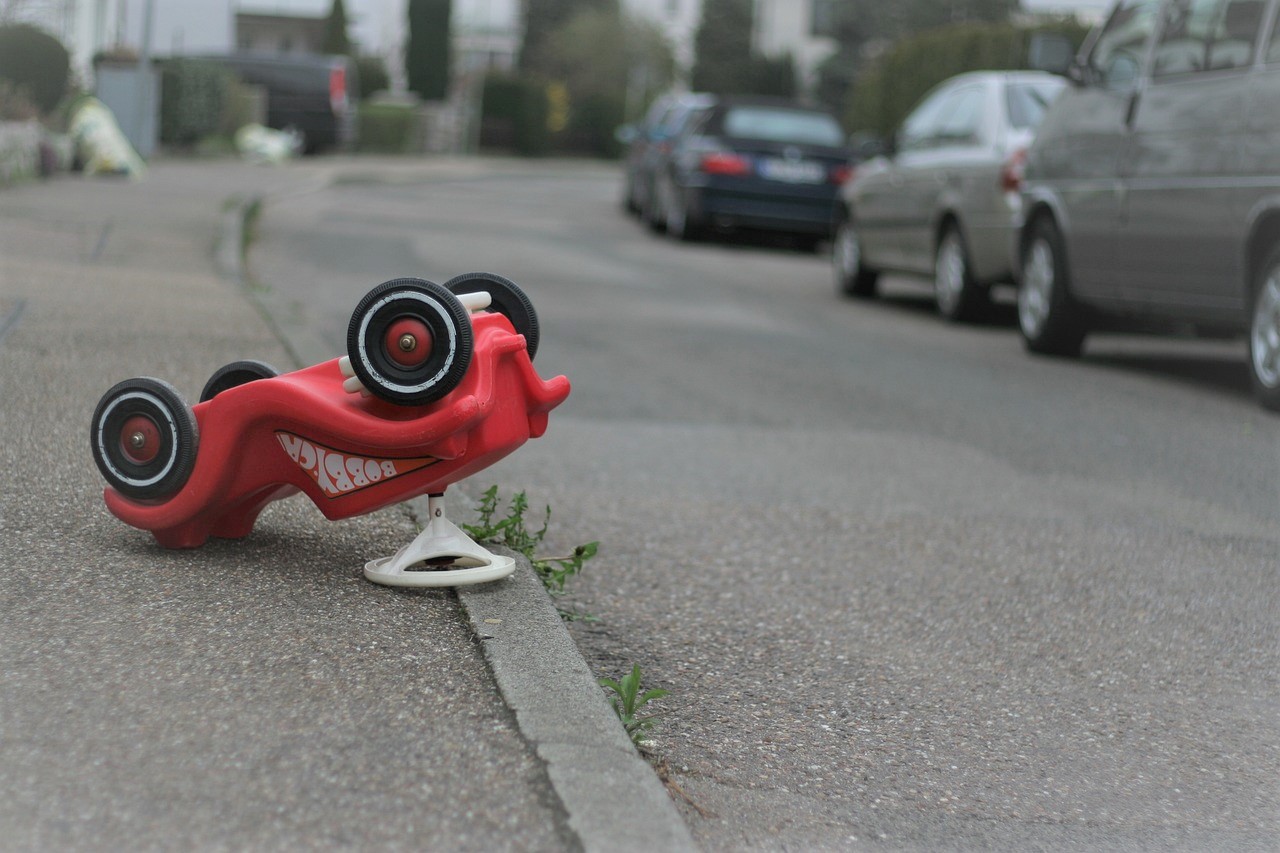 Un coche de juguete rojo, volcado en la carretera como un siniestro